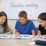 Zwei Schülerinnen und ein Schüler blicken in ihre Schulbücher und praktizieren das Aussprache-Training Shadow Reading